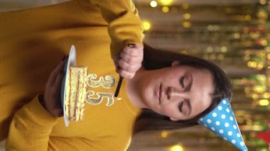 Doğum günü pastasında 35 numaralı mumları çakmakla yakan kadın. Gülümseyen kız doğum günü pastası tutuyor ve partide kameraya bakıyor. Bakış açısı. Dikey video