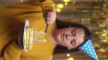 Doğum günü pastasında 35 numaralı mumları çakmakla yakan kadın. Gülümseyen kız doğum günü pastası tutuyor ve partide kameraya bakıyor. Bakış açısı. Dikey video