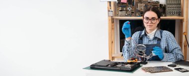 Laptop tamiri. Teknik destekte çalışan tamirci çoklu metre ya da voltaj ölçer kullanarak bilgisayar laptopunu tamir ediyor. Uzayı kopyala Pankart
