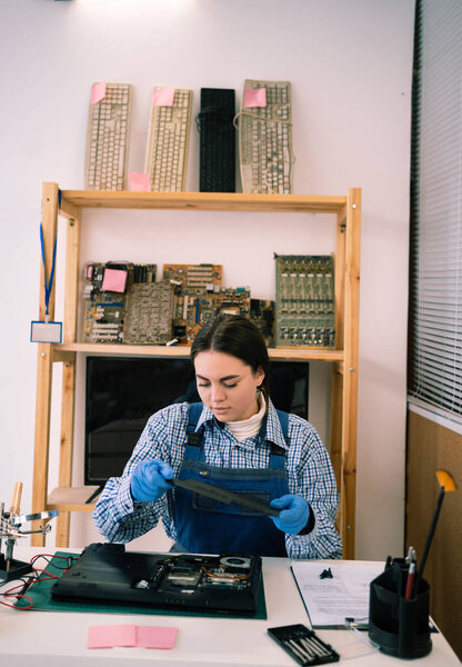Laptop disassembling at electronic repair shop or workshop. Woman engineer separating laptop case. Electronic renovation, business, occupation concept