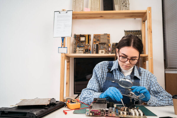 Engineer fixing broken computer motherboard using tweezers. Electronic repair shop, technology development concept