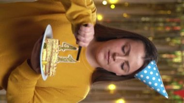 Elinde doğum günü pastası tutan güzel, mutlu, genç bir kadın 41 numaralı altın mumla çakmakla yanıyor. Doğum günü ve yıldönümü kutlaması kavramı. Bakış açısı. Dikey video