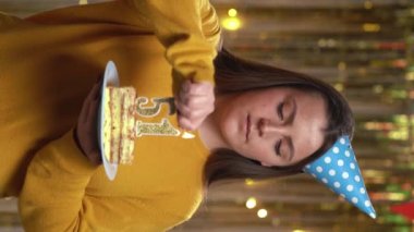 Elinde doğum günü pastası tutan güzel, mutlu, genç bir kadın. 51 numaralı altın mum çakmakla yanıyor. Doğum günü ve yıldönümü kutlaması kavramı. Bakış açısı. Dikey video
