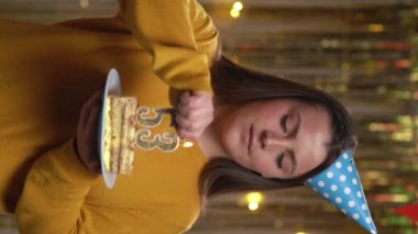 53 numaralı doğum günü pastasını tutan süveter giyen güzel, mutlu genç bir kadın çakmakla yanan altın mumlar. Doğum günü ve yıldönümü kutlaması kavramı. Bakış açısı. Dikey video