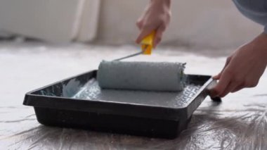 Tabladaki boya silindirini kapat. Kapalı alanda boya silindiri kullanan bir kadın. Ressam ve dekorasyon için aletler. Boşluğu kopyala