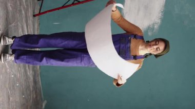 Yeni evde kağıt planlı mutlu bir kadın. Taşındıktan sonra evde tadilat. Evi yeniden tasarlıyorum. Dikey video