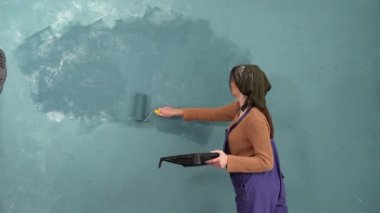 Duvarı boyayan kadın. Duvarı boyayan boya silindirli kız. Tamir ve ev yenileme konsepti. Boşluğu kopyala