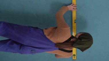 İşçi, duvarın ruhsal bir seviyede düz olup olmadığını kontrol ediyor. Tamir, inşaat ve inşaat konsepti. Dikey video. Boşluğu kopyala