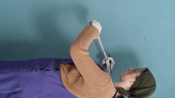 测量墙的尺寸的女人 在家居翻新过程中 用施工胶带测量蓝色墙 垂直录像 复制空间 — 图库视频影像