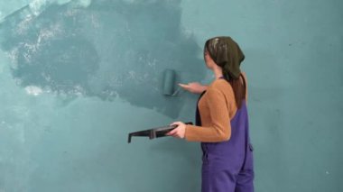 Dekoratör beyaz duvarı mavi renkle silindirle boyuyor. Tamir ve ev yenileme konsepti. Boşluğu kopyala