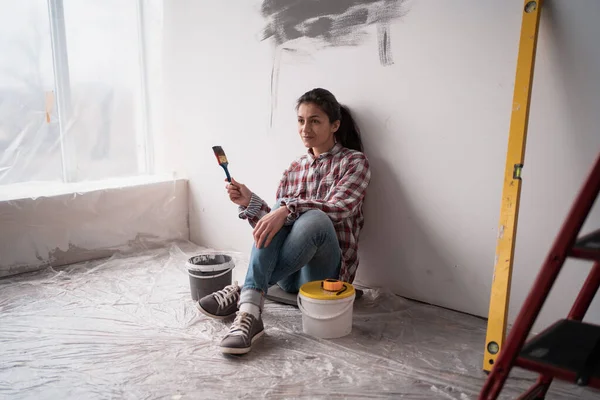 Happy woman with paint dreams of renovating a house and planning a design project. Concept of repair in the apartment. Copy space