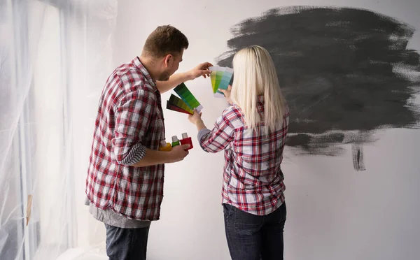 Couple renovating their apartment, woman holding color palette and man choice wall color. Home, moving, decoration, renovation, and wall painting concept