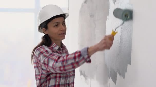 在灰色的新房子里 只有白人妇女一个人在粉刷房间 女性用滚轮刷重新设计公寓翻新家庭油漆墙 复制空间 — 图库视频影像