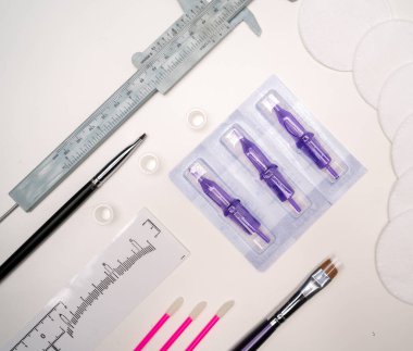 Beyaz arka planda mikro pigmentasyon ekipmanlarının üst görüntüsü. Mikro patinaj malzemeleri. Kalıcı makyaj konsepti. Düz yatıyordu