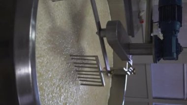 Peynir fabrikasındaki çelik paslanmaz tankta kaymak ve süt. Süt ürünleri konsepti. Dikey video