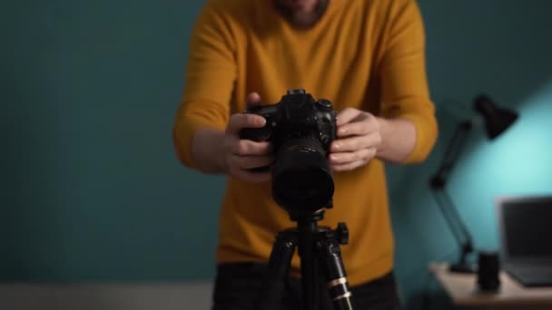 夕方に自宅で働くプロのデジタルカメラで写真を撮る若い男は 手とレンズに焦点を当てます — ストック動画