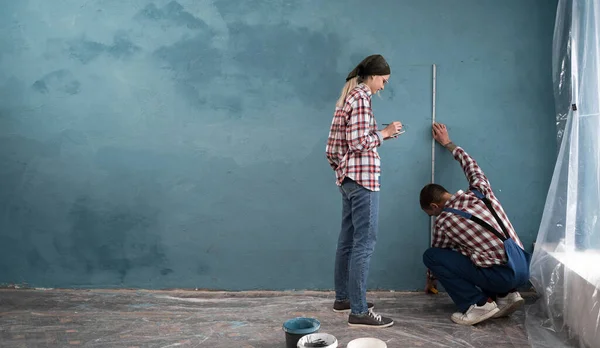 stock image Young couple measuring wall with tape ruler, in their new house, doing home repairing. Copy space