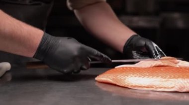 Somon Japon şefin elinde. Sashimi ve suşi için somon filetosu dilimlemek için bıçak kullanıyor. Deniz ürünleri yemeği için. Kapat.