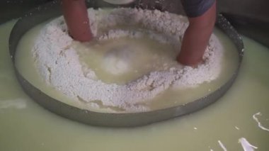 Peynir fabrikasında çalışan işçiler tanktan kaymak söküyor. Peynir üretim sürecinin bir parçası