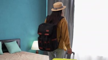 Otele giriş yaptıktan sonra otele bavulu olan İspanyol turist kadın dinlenmek için yatakta oturuyor. Seyahat ve tatil kavramı