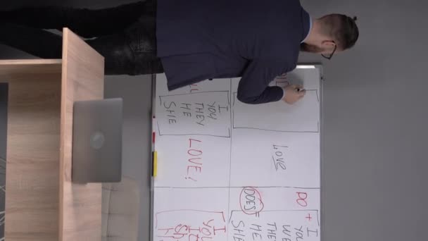 教育和电子学习概念 男教师站在白板前 用笔记本电脑向学生解释语法规则 在黑板上写东西 垂直录像 — 图库视频影像