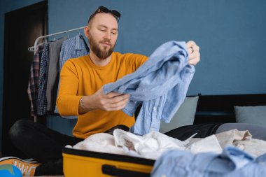 Yatak odasında yolculuk için bavul hazırlayan bir adam. Seyahat konsepti. Boşluğu kopyala