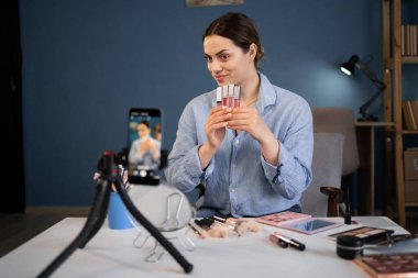 Kadın mikro etkileyici canlı viral video kamerayı ev stüdyoda kaydediyor. Medya hobisi. Vlog kadın ruj gösteriyor. Güzellik blogcusu kavramı