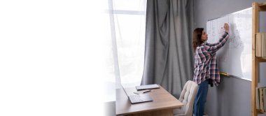 Sınıfta yazı tahtasının yanında kadın öğretmen, tahtaya İngilizce kelimeler yazıyor. Modern meslek çevrimiçi öğretmendir. Pankart. Boşluğu kopyala