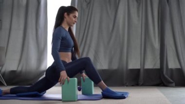 İnce kız yoga bloklarıyla esneme hareketleri yapıyor, spor kıyafetleri giyiyor, spor yapıyor, uzun boylu, fotokopi çekiyor.
