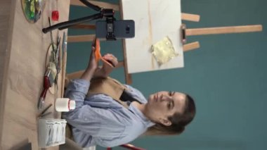 Resim atölyesinde ana sınıfı çevrimiçi olarak yayınlıyor. Profesyonel kadın sanatçının konuşma becerisi ve çizim teknikleri özel ders videosu kaydetmek için akıllı telefon kamerası kullanması. Dikey video