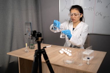 Çevrimiçi öğretmen, akıl hocası. Okulun fen dersi. Öğretmen kimyayı açıklıyor. Genç bir kadın video dersleri veriyor ve kaydediyor. Önündeki tripoda akıllı telefon takıyor. Boşluğu kopyala