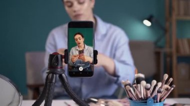 Akıllı telefon ekranına yakın plan, sosyal medya nüfuzlu kadınlar makyaj ürünleri ve aksesuarları öneriyor. Rujun farklı tonlarını gösteriyor. Kayıt video günlüğü, İnternet iş dünyası güzelliği