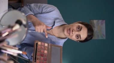 Sosyal medya uzmanı kadın makyaj ürünleri ve aksesuarlar öneriyor, göz farı incelemesi olumsuz. Kayıt video blogu, internet iş dünyası güzellik blogcuları. Pov webcam görüntüsü. dikey video