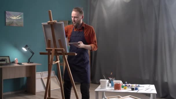 筆を手にした忙しいアーティストが居心地の良いスタジオで油絵を描いています 才能ある若い芸術家がキャンバスに絵を描く 絵画の概念 趣味で仕事をする コピースペース — ストック動画