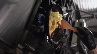 Şef tavada tavuklu erişte pişiriyor, tavada kremalı makarna ve ateşte yanıyor. Büyük plan. dikey video