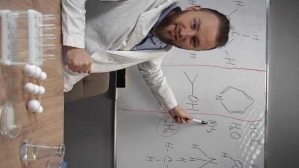 Ein Chemielehrer Oder Tutor Schaut Die Kamera Zeigt Auf Ein — Stockvideo