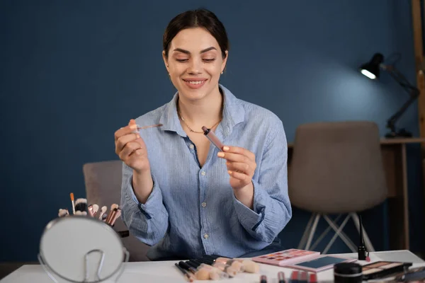 Beauty blogger caucasian young woman is broadcasting and recording the broadcast on a smartphone. holds lipstick in her hands makes a review of cosmetic products in a makeup video blogger.