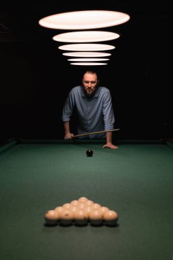 Sakallı beyaz bir adam bilardo masasının yanında duruyor ve oyuna hazırlanıyor. Bilardo sporu konsepti. Boşluğu kopyala.