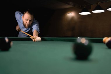 Bilardo oyununun bir parçası devam ediyor. Amerikan bilardosu. Bilardo oyunu. Bilardo sporu konsepti. Genç profesyonel bir adam karanlık bir kulüpte oynuyor.