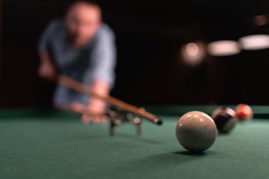 Bilardo salonunda bilardo oynayan bir adam topa vurmaya çalışıyor. Bilardo konsepti. Seçici odak