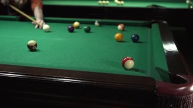 Elinde bilardo topuna nişan almış, topları deliğe sokmuş. Yakın plan.