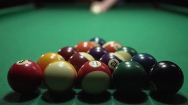 Adam bilardoda ıstaka ile bir piramit bilardosuna vuruyor. Gece hayatı. Bilardo konsepti