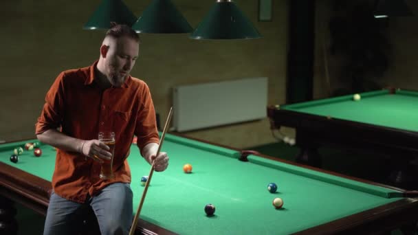 年轻的高加索人坐在酒吧的台球桌上喝啤酒 复制空间 — 图库视频影像