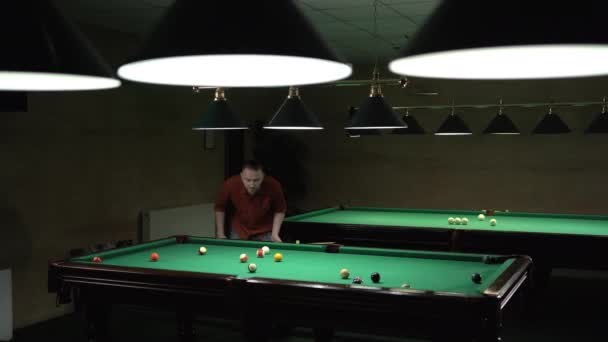 ビリヤードクラブで緑の表面とボールとビリヤードテーブルの近くに白人ハンサムな男 プールゲームのコンセプト スペースのコピー — ストック動画