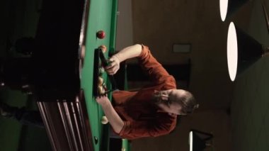 Beyaz tenli oyuncu bilardo masasında bilardo toplarını topluyor. Hobi ve eğlence konsepti. Dikey video
