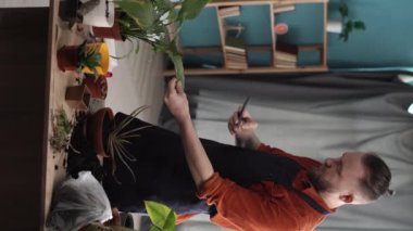 Endişeli adam elinde akıllı telefondan ev bitkisi hastalıkları, güneş yanığı, kimlik tespiti ve tedavisi hakkında bilgi okuyor..