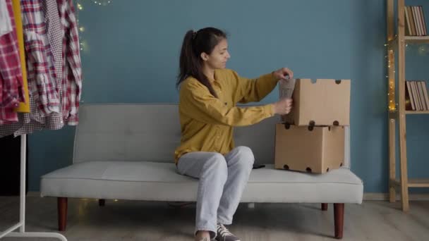 服の寄付のための段ボール箱を準備する女性 寄付する前に家で服を準備する 寄付の考え方 — ストック動画