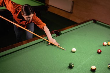Kadın bilardo toplarını masaya vuruyor. Bir çift taşak. Yeşil kumaş üzerinde bilardo oyunu. Üst görünüm