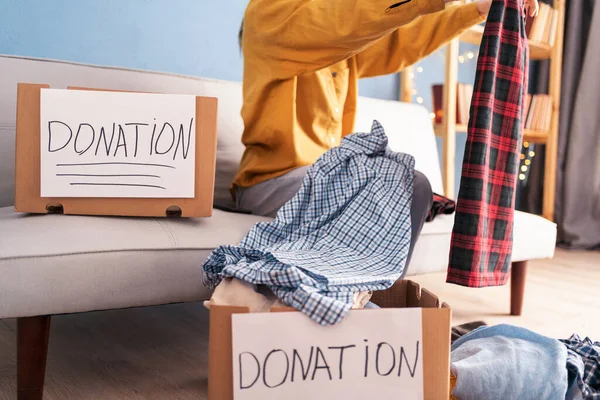 Woman Puts Clothes Donation Box While Sitting Sofa Her Room — Stock Photo, Image