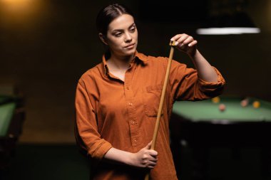 Güzel bilardo oyuncusu Snooker yeşil masaların yanında hareketli ıstakayı tebeşirliyor. Yakın plan.